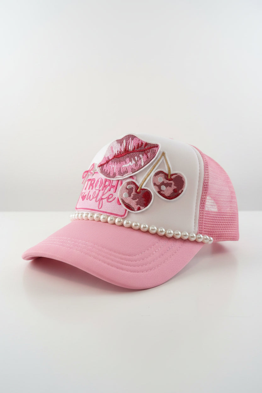 Pink and white cap with 'Trophy Wife' text and decorative elements on a light gray background