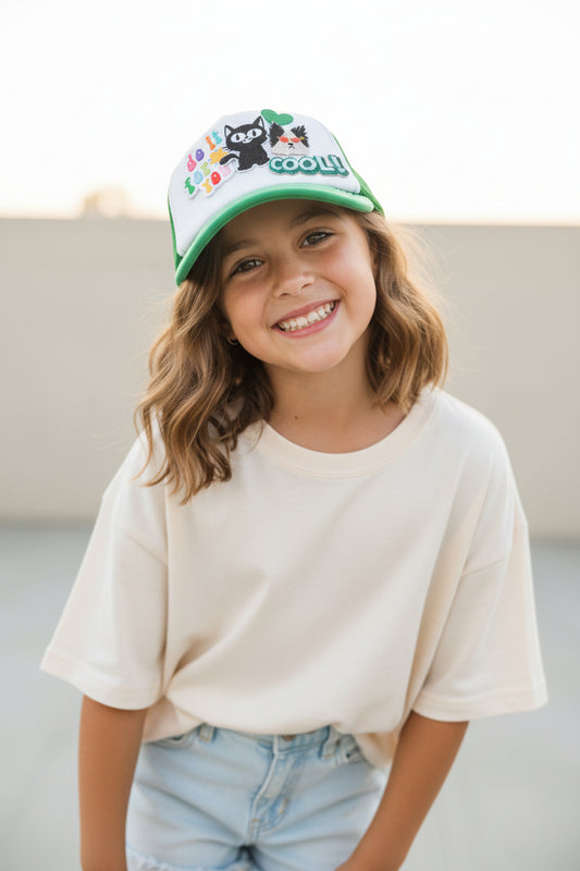 Green and white cap with cartoon cat design and text on a surface