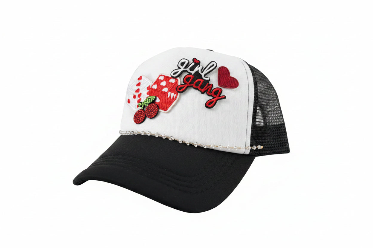 Black and white cap with 'girl gang' text and red heart design on a surface.