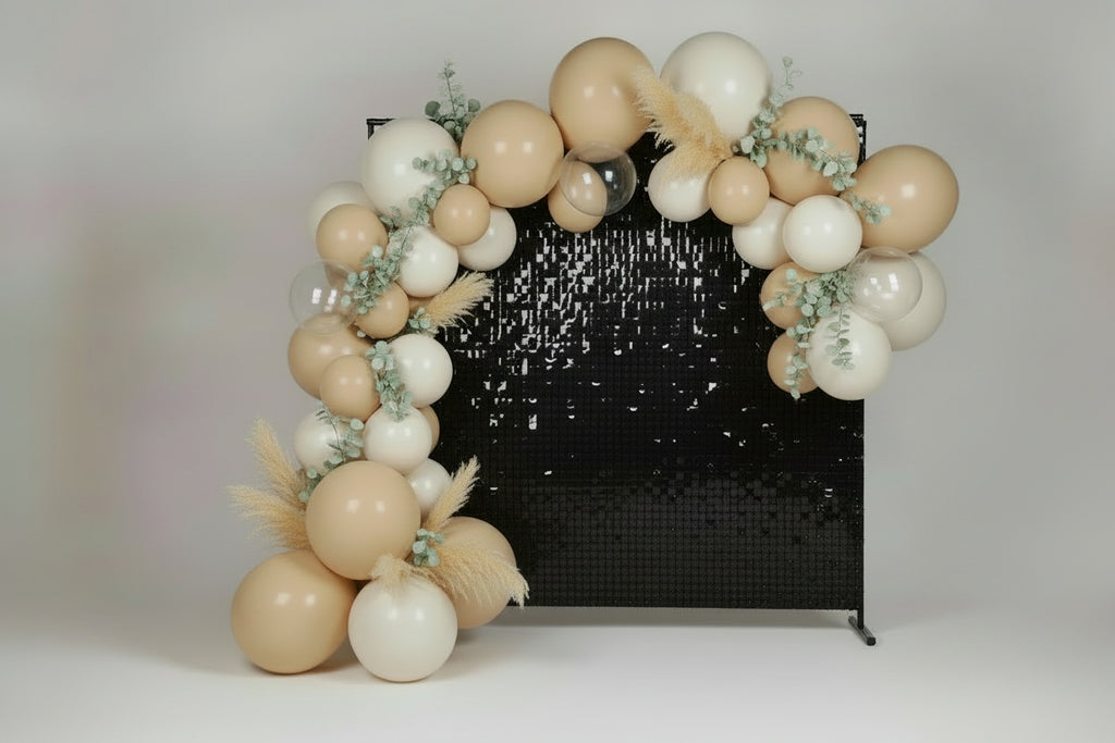 Cream and white balloon arch with a black sequin backdrop.
