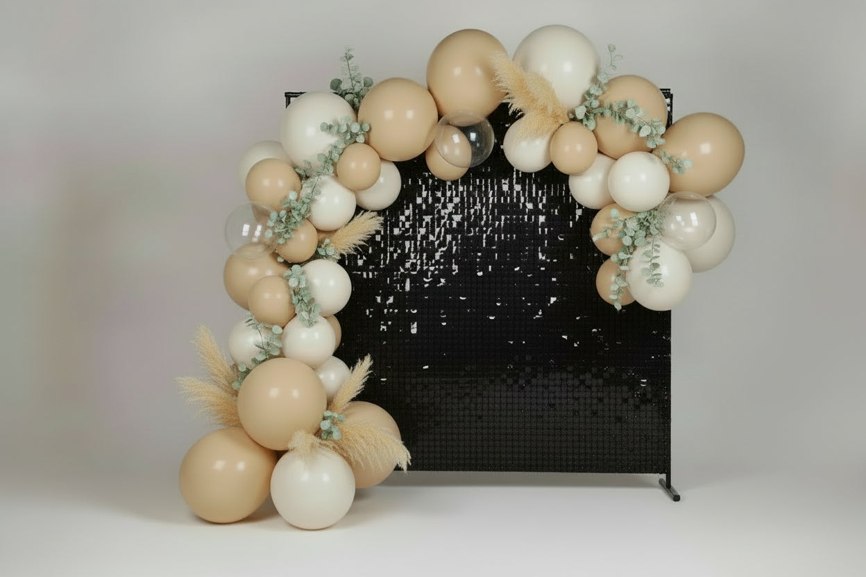 Cream and white balloon arch with a black sequin backdrop.