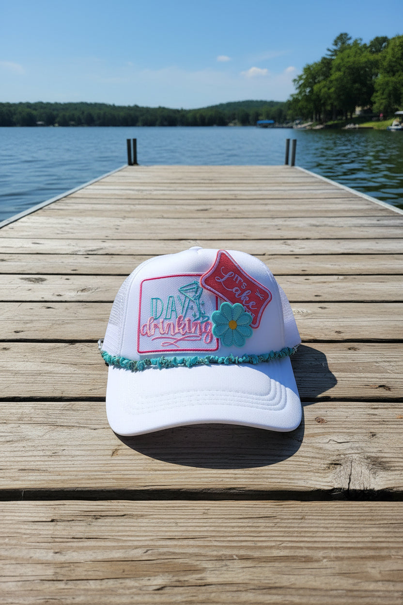 White hat with embroidered text and floral design on a textured surface